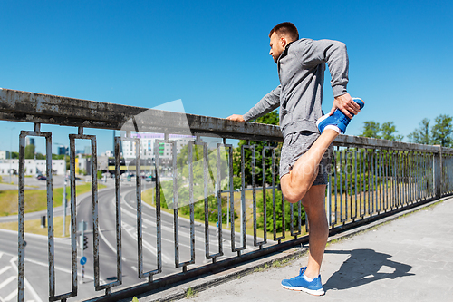 Image of man stretching leg on bridge