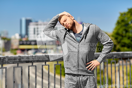 Image of man stretching neck on bridge