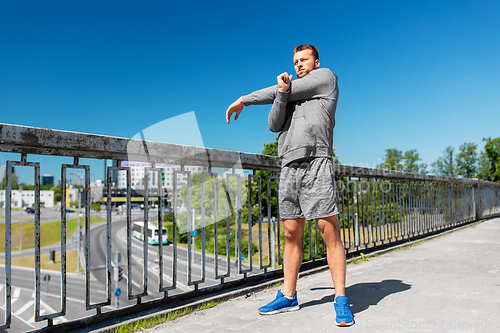 Image of man stretching hand and shoulder on bridge