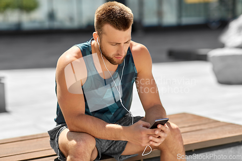 Image of young athlete man with earphones and smartphone