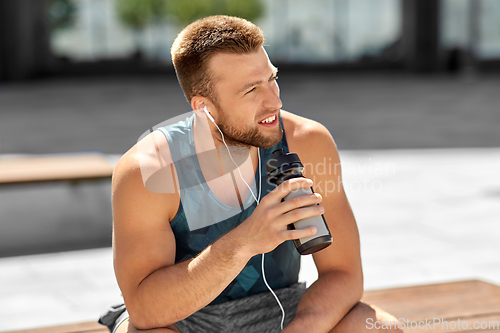 Image of sportsman with earphones and bottle in city