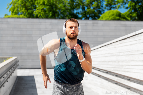 Image of young man in headphones running outdoors