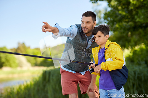 Image of happy smiling father and son fishing on river