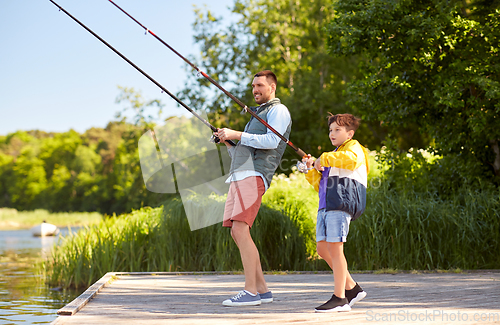 Image of happy smiling father and son fishing on river