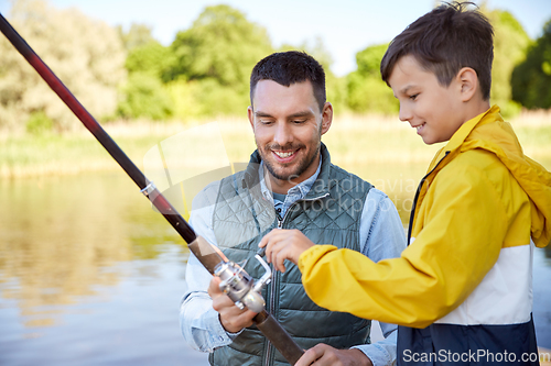 Image of happy smiling father and son fishing on river