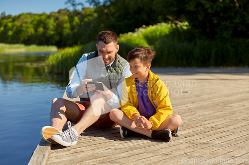 Image of father and son with smartphone on river berth