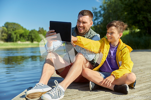 Image of happy father and son with tablet pc on river berth