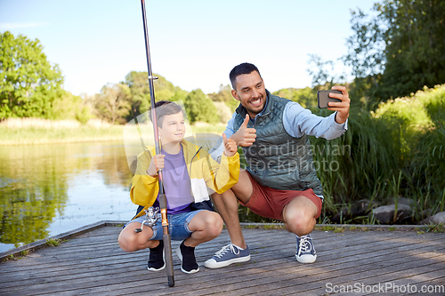 Image of father and son with fishing rods taking selfie