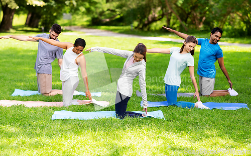 Image of group of people doing yoga at summer park