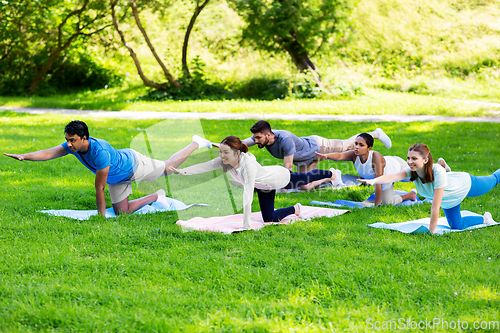 Image of group of people doing yoga at summer park