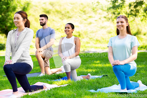 Image of group of people doing yoga at summer park