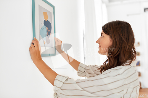 Image of woman decorating home with picture in frame