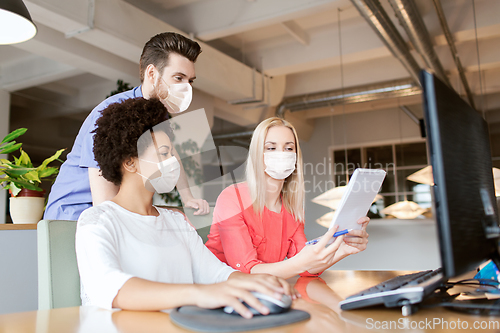 Image of creative team in masks with computer in office