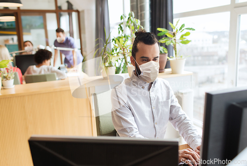 Image of creative male office worker in mask with computer