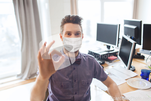 Image of male office worker in mask showing ok sign
