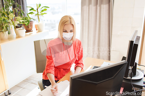 Image of female office worker in mask with computers