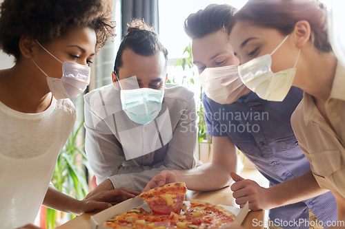 Image of business team eating in masks pizza at office