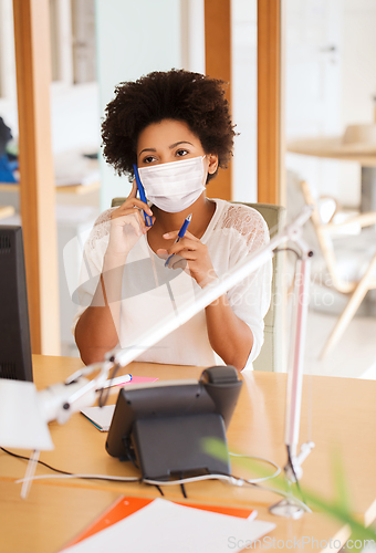 Image of businesswoman in mask calling on phone at office