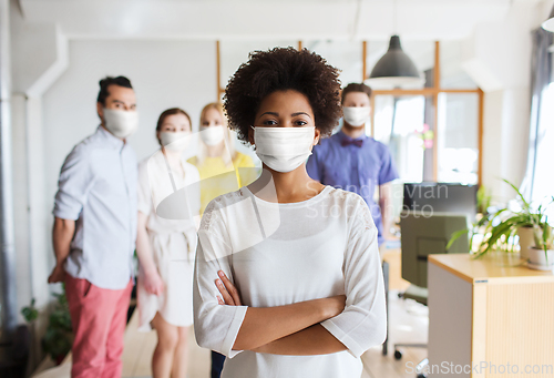 Image of woman in mask over creative team at office