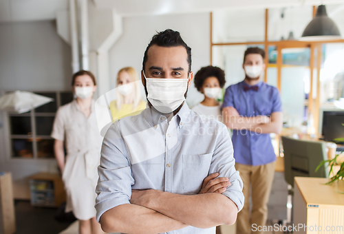 Image of young man in mask over creative team in office