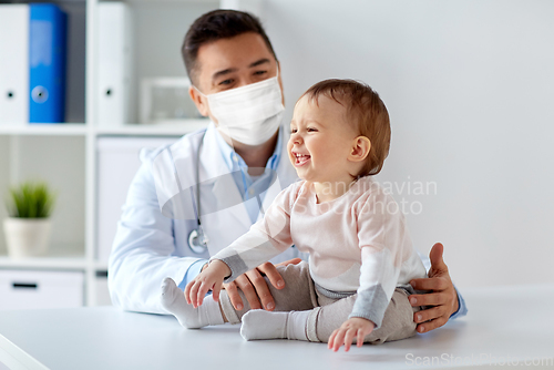 Image of doctor or pediatrician in mask with baby at clinic