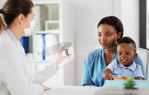Image of doctor in mask and woman with son at clinic