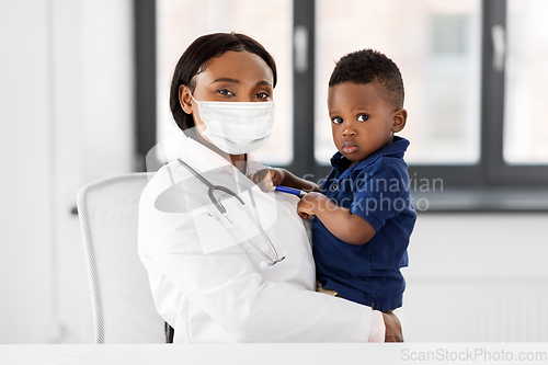 Image of doctor in mask with baby patient at clinic