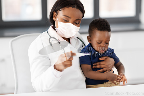 Image of doctor in mask measuring baby's temperature