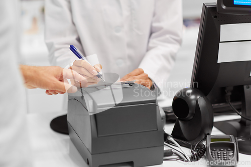 Image of pharmacist and customer at cash register