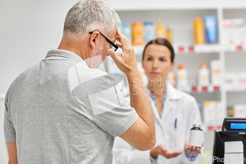 Image of pharmacist and old man with medicine at pharmacy