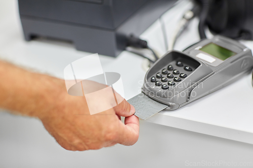 Image of close up of hand with credit card in card-reader