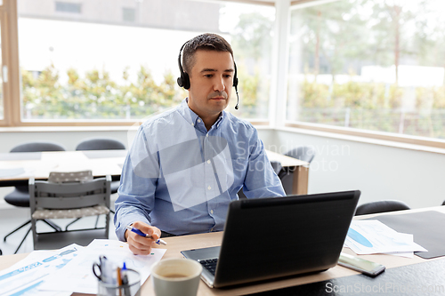 Image of man with headset and laptop working at home