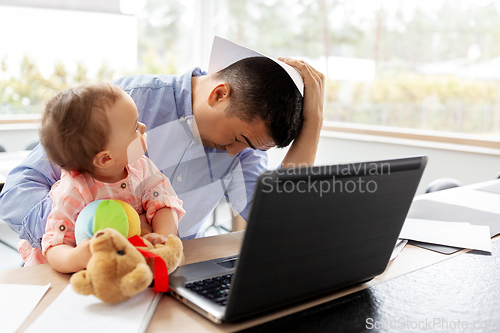 Image of father with baby working on laptop at home office