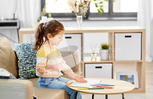 Image of little girl drawing with coloring pencils at home