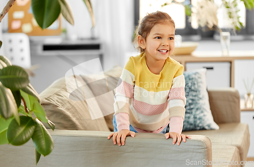 Image of happy smiling little girl on sofa at home