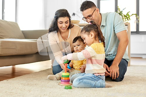 Image of happy family playing with pyramid toy at home