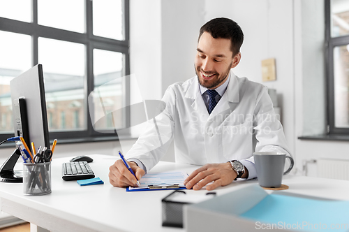 Image of smiling male doctor with clipboard at hospital