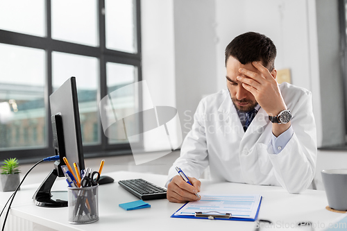 Image of stressed male doctor with clipboard at hospital