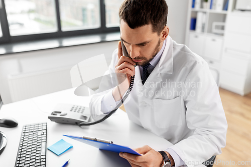 Image of male doctor calling on desk phone at hospital