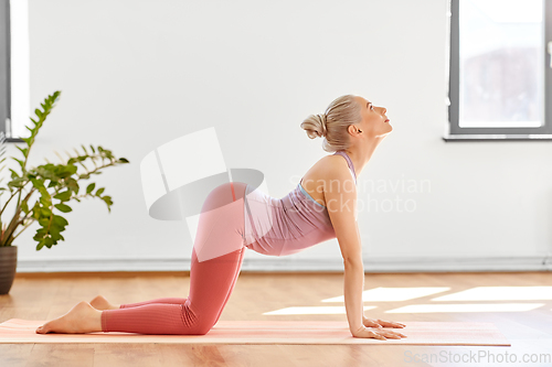 Image of young woman doing cow pose at yoga studio