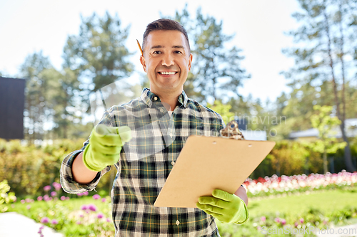 Image of man with clipboard pointing to camera at garden