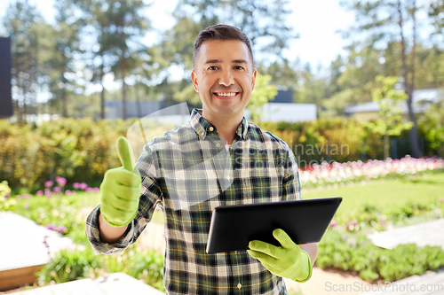 Image of man with tablet pc showing thumbs up at garden