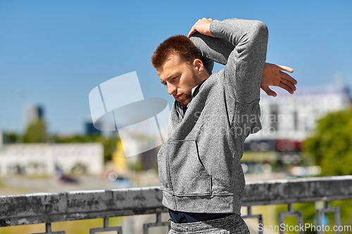 Image of man stretching hand and shoulder on bridge