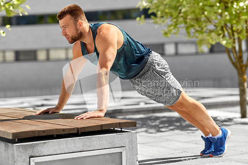 Image of young man doing push ups on city street