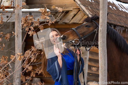 Image of Joyful girl plays with a horse, the horse shows teeth