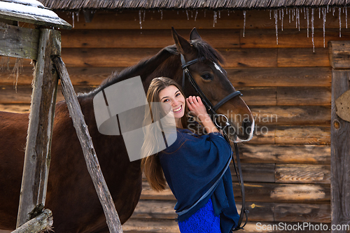 Image of Portrait of a girl hugging a horse against the background of a wall of logs