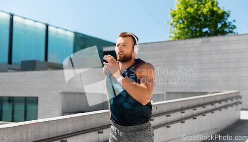 Image of young man in headphones running outdoors