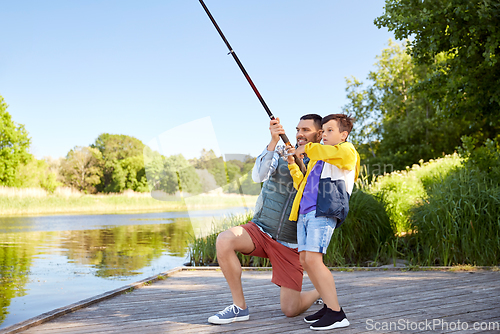 Image of happy smiling father and son fishing on river