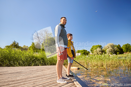 Image of happy smiling father and son fishing on river