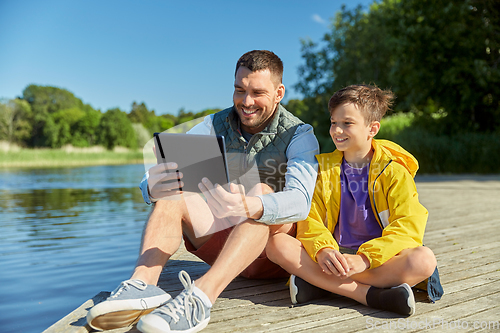 Image of happy father and son with tablet pc on river berth